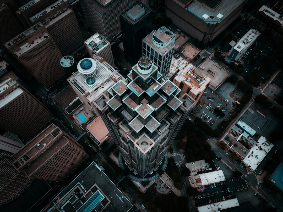 High-angle aerial view looking down on a downtown tower, its stepped roofline and the surrounding rooftops, the kind of subject a 3D model from drone photos captures