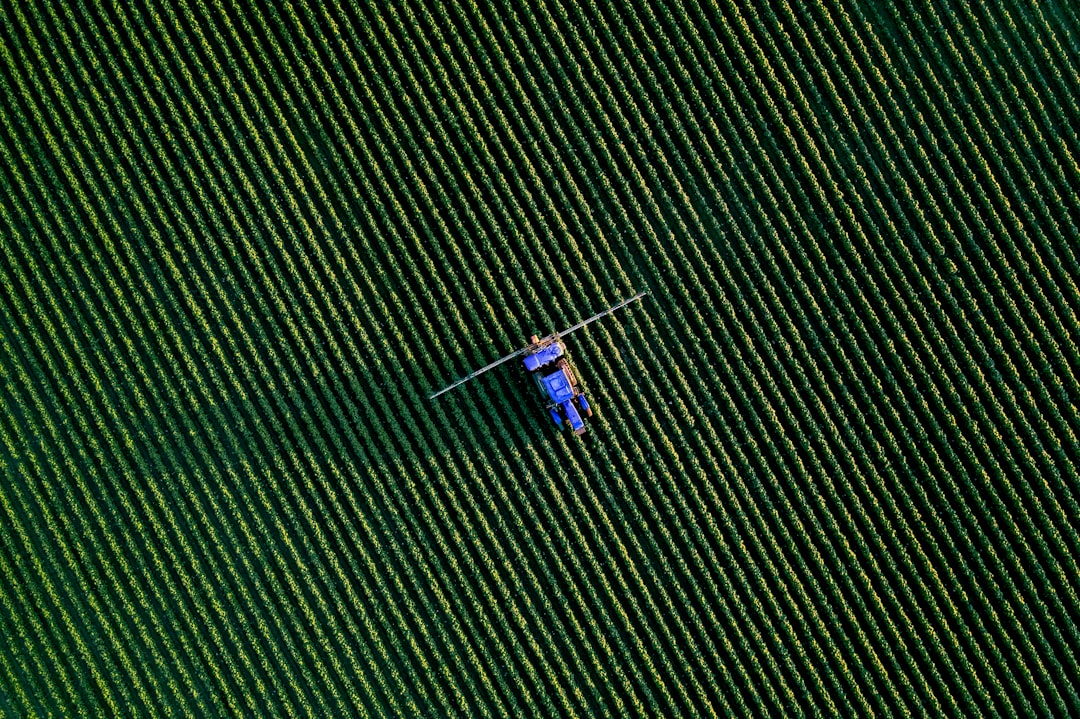 Aerial view of a boom sprayer working a green crop field, the kind of application work agriculture drone software plans, controls and records