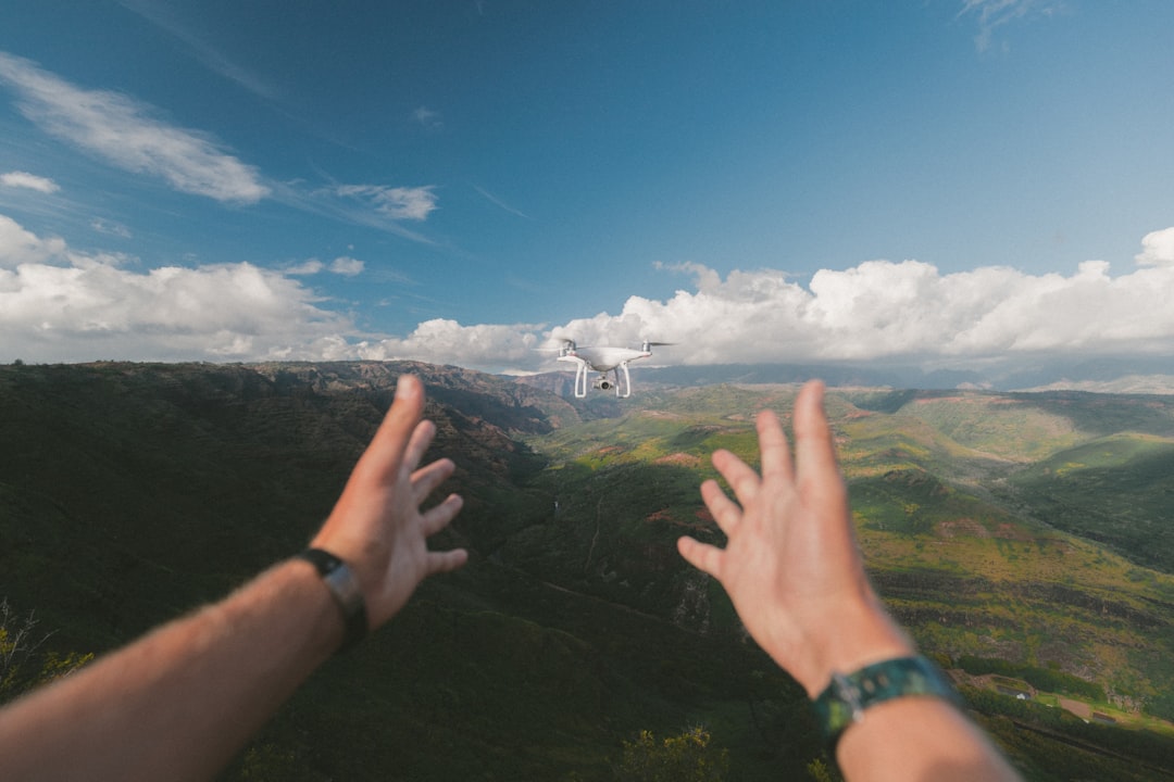 Recreational drone pilot launching a quadcopter in an open field while checking airspace on a phone