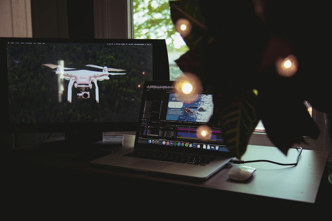 Drone on a desktop monitor beside a laptop running drone management software