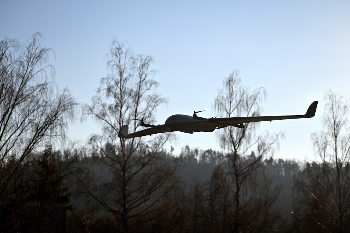 Fixed-wing VTOL drone flying over a forested landscape during a beyond visual line of sight mission