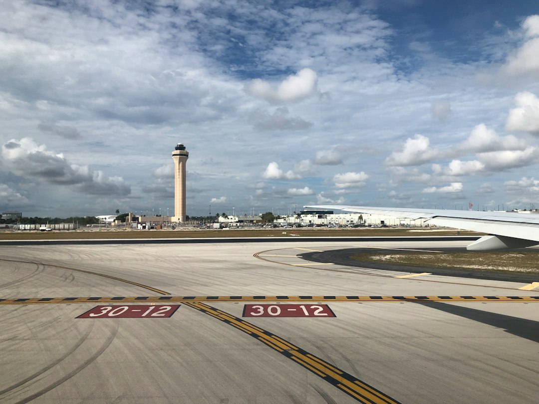 Airport control tower seen past a runway hold-short marking, the kind of towered airport where drone pilots need authorization for controlled airspace