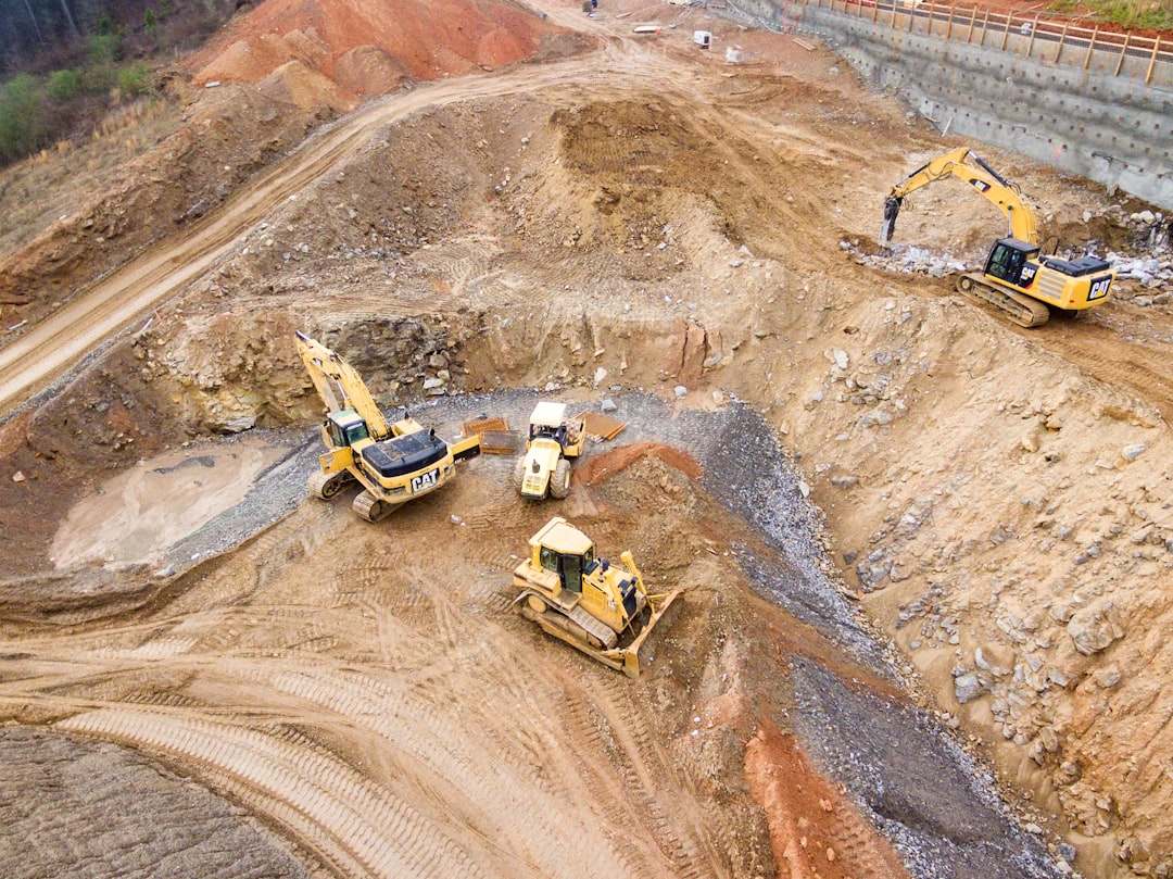 Aerial drone view of a commercial construction site with excavators and heavy equipment working on earthmoving operations
