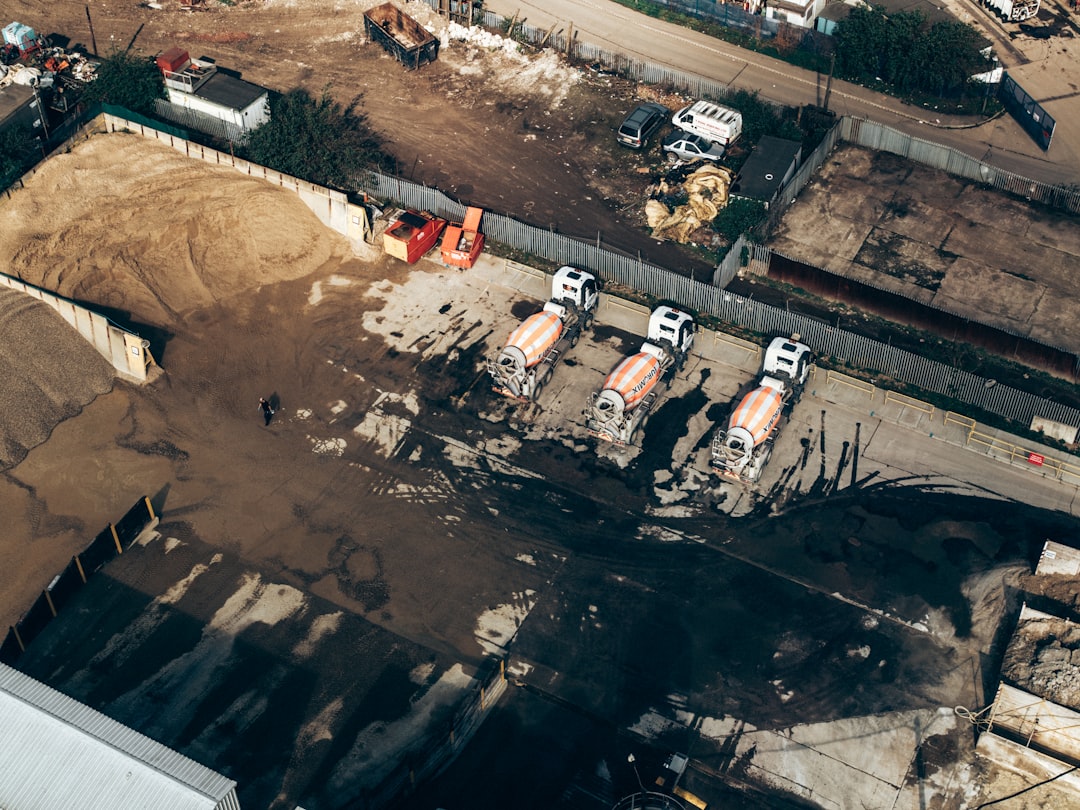 Aerial drone view of an active construction site with concrete mixer trucks, earthworks and fenced site access, illustrating construction drone software capture workflows