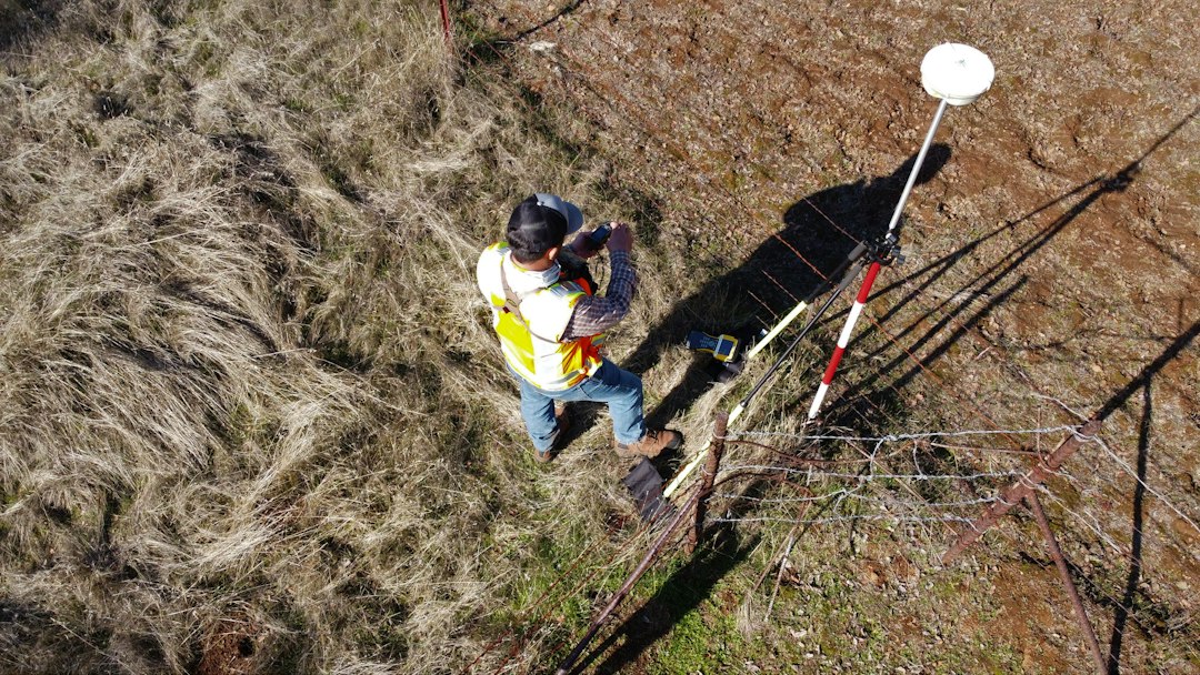 Overhead drone photo of a surveyor with a GNSS rover pole collecting ground control on a field site for a DJI Terra mapping project
