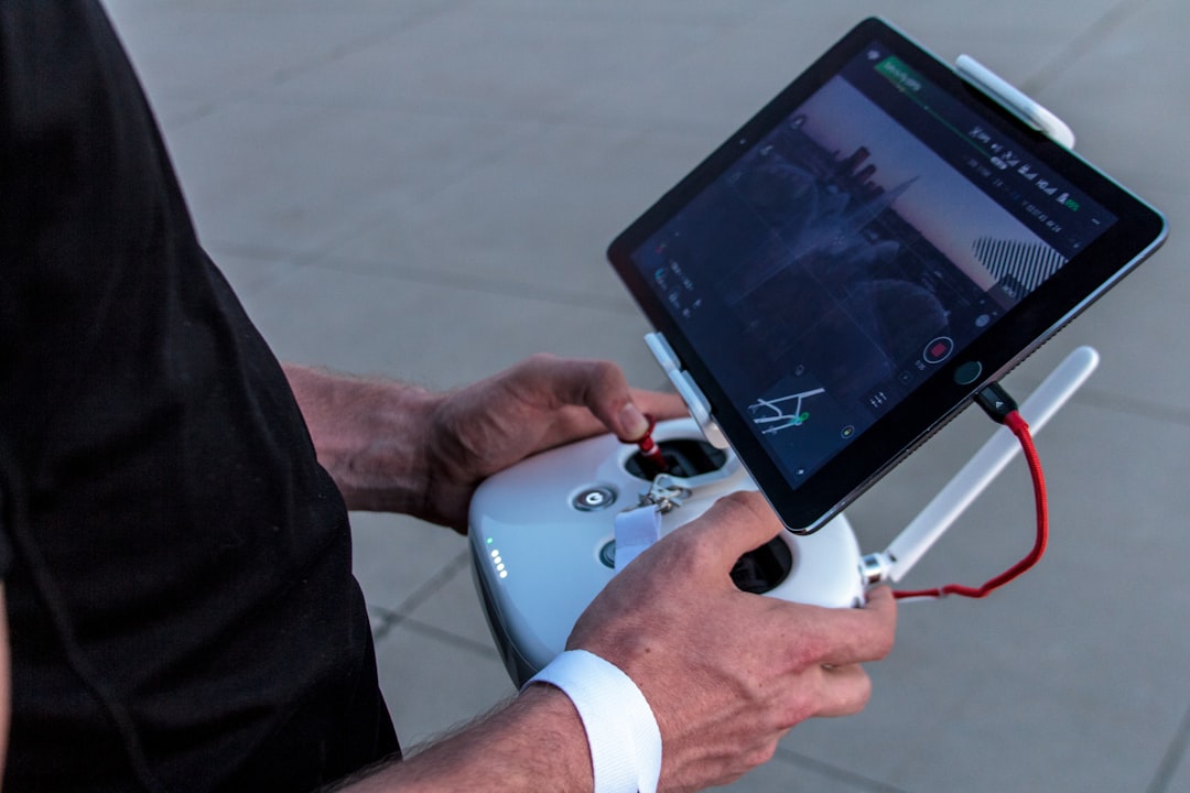 Commercial drone pilot holding a controller and tablet showing live flight data logged after a Part 107 flight