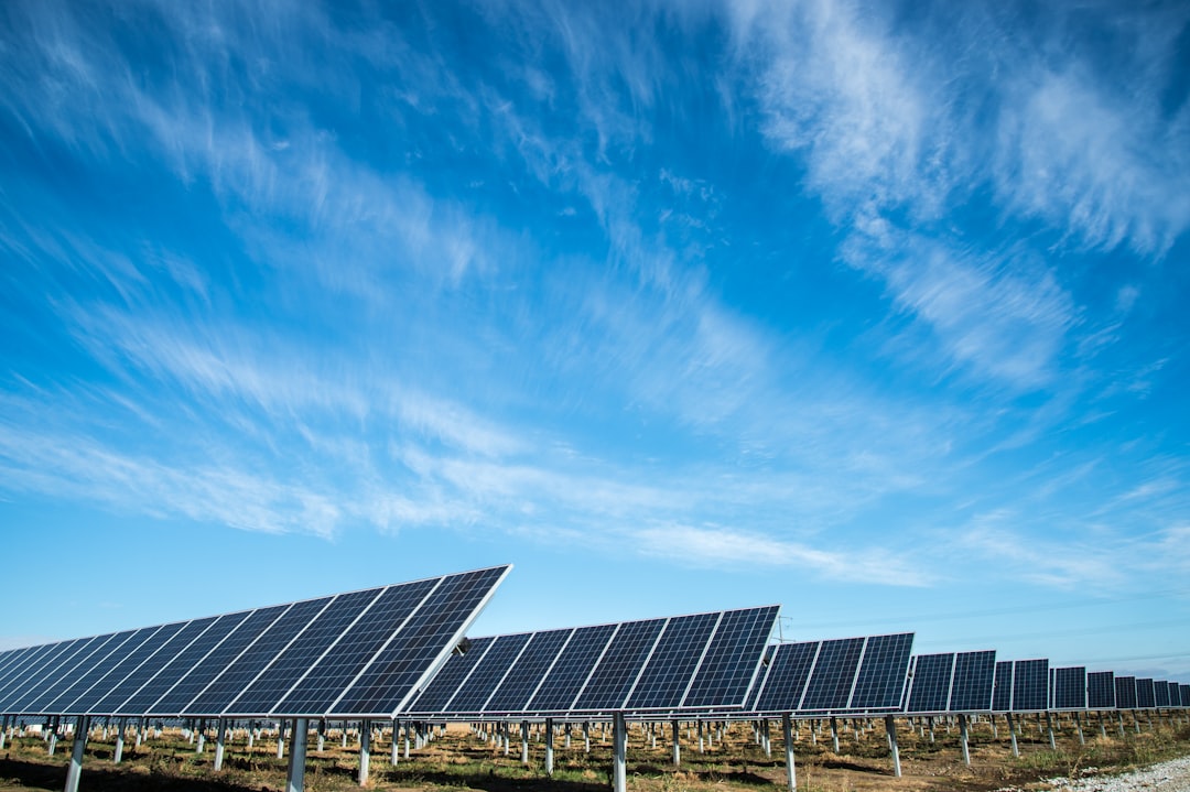Drone equipped with thermal camera inspecting rows of solar panels at a utility-scale solar farm