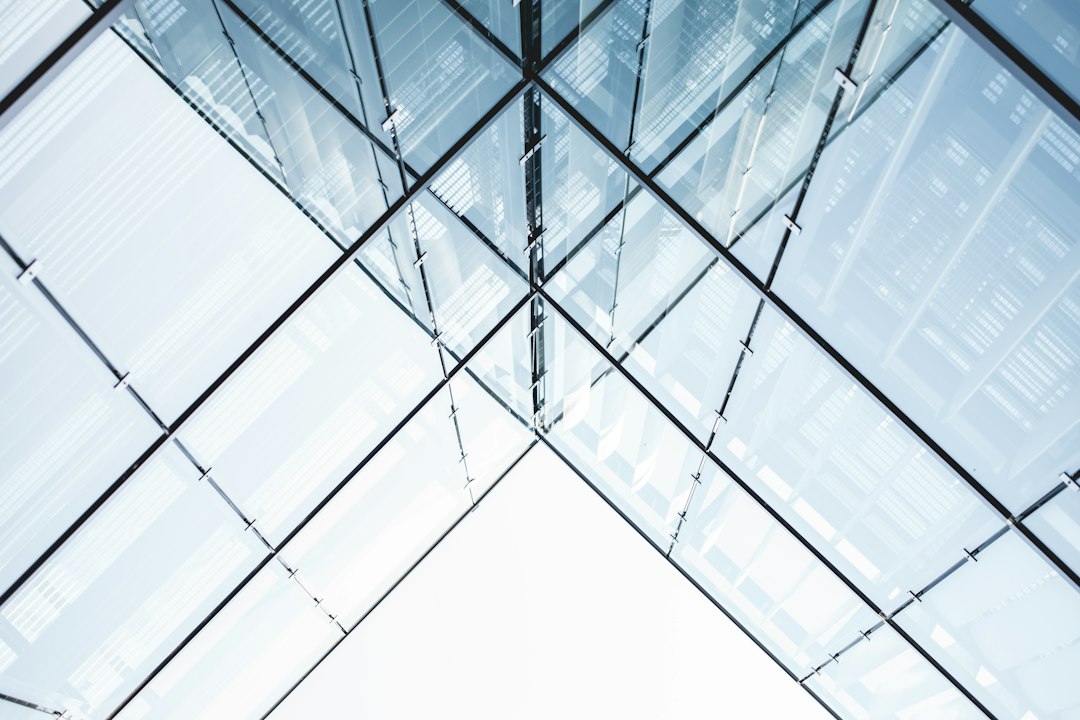 Looking up at a glass curtain wall on a commercial building, the kind of exterior drone window cleaning services wash