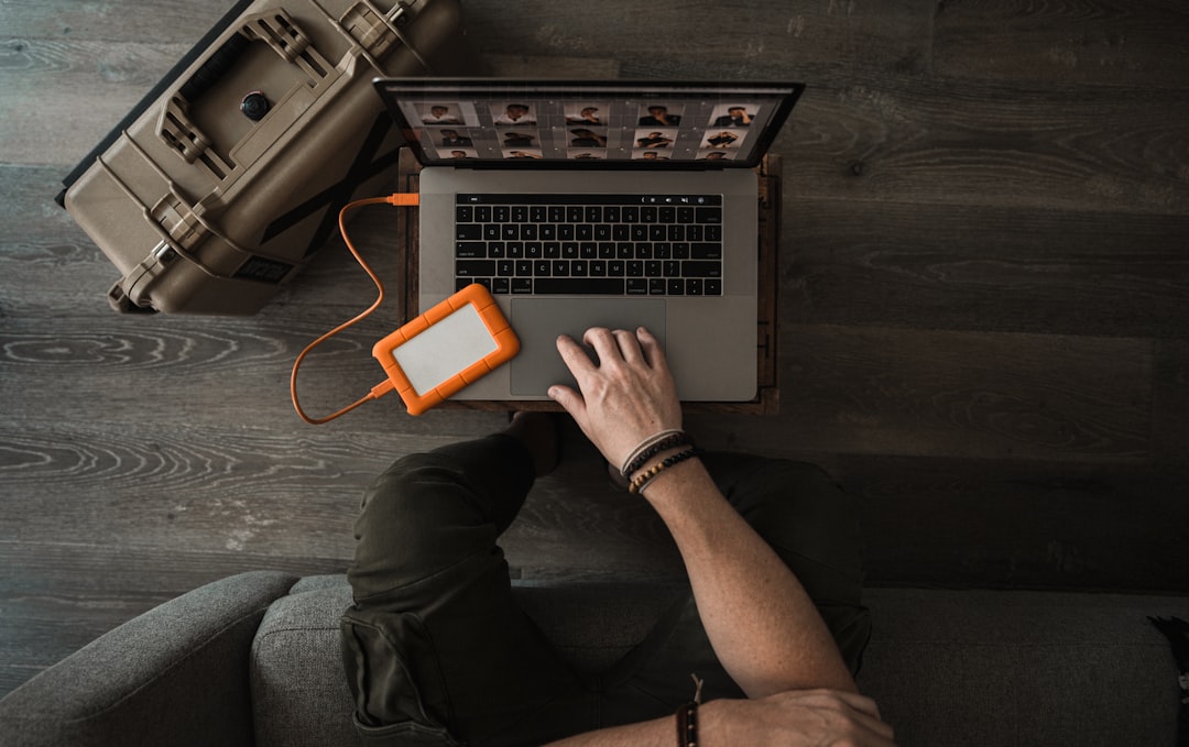 Drone operator performing an FAA drone registration lookup on a laptop beside a rugged equipment case and external drive