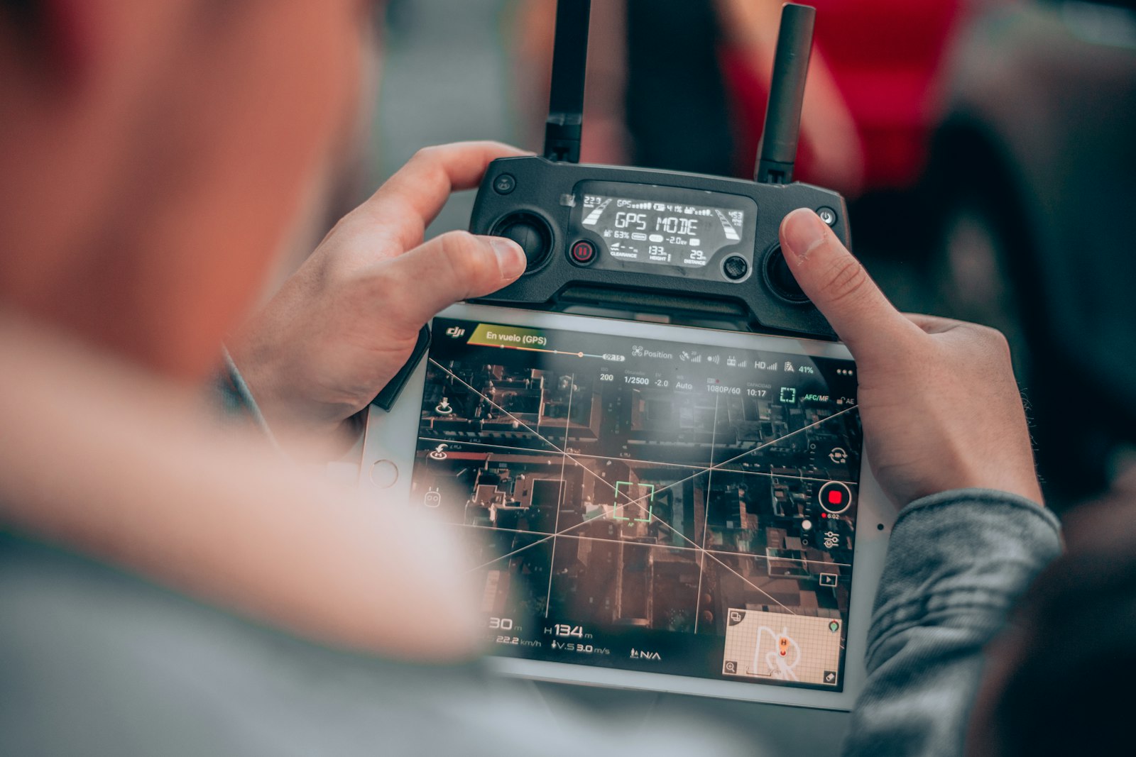 Drone pilot holding a remote controller with a live map on the tablet screen, the kind of crew role Part 108 would qualify through operator training