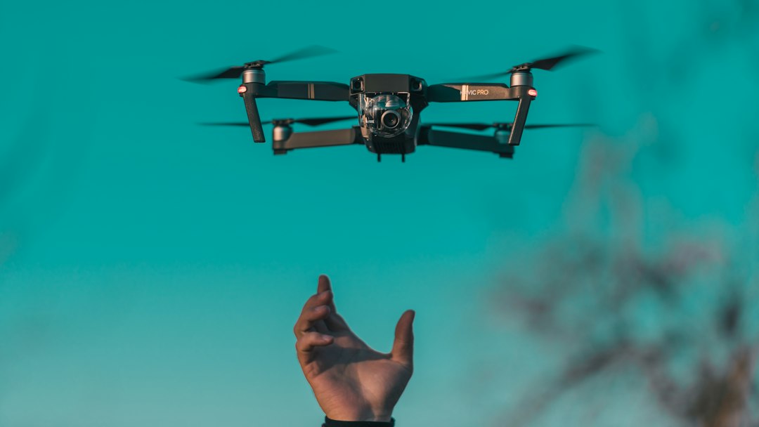 Camera drone hovering above a raised hand, the kind of aerial photo capture Pix4D pricing plans charge to process