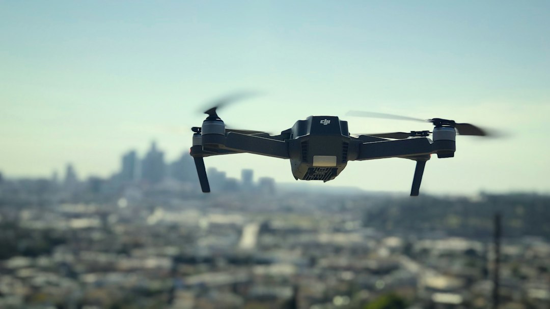 Small quadcopter drone hovering above a hazy city skyline, the kind of urban airspace where police drone programs operate