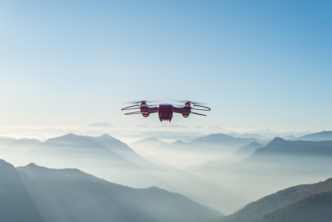 Commercial UAS drone hovering above misty mountain ridges during a professional flight operation
